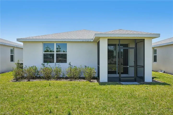 Back of house featuring a yard, stucco siding, a sunroom, and a shingled roof