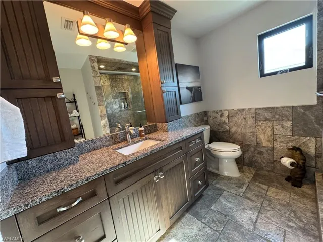 2ND UPSTAIRS Bathroom with vanity, tile walls, an enclosed shower, and toilet