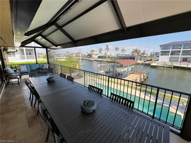 Wooden terrace featuring a patio area, a water view, a dock, an outdoor hangout area, and a fenced in pool