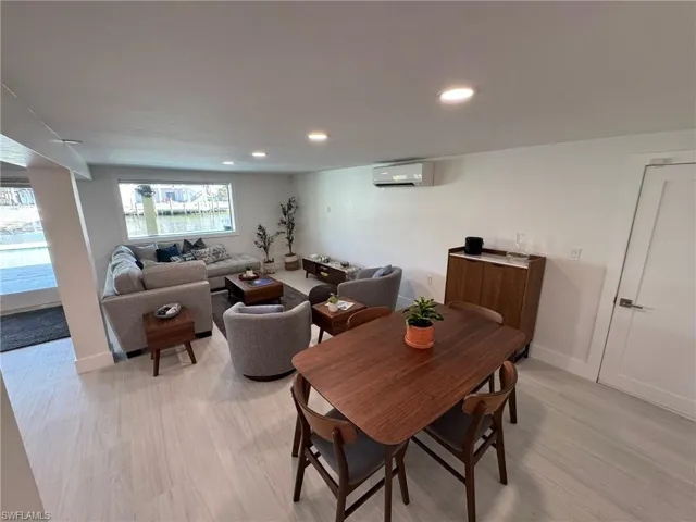 DOWNSTAIRS Dining area with light wood-type flooring and an AC wall unit