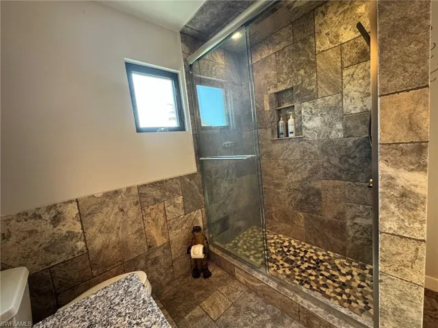 2ND UPSTAIRS Bathroom with walk in shower, toilet, and tile walls