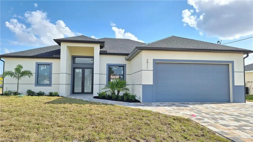 View of front of house with a front lawn, stucco siding, a garage, and roof with shingles