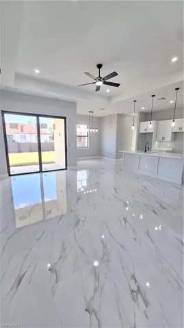 Unfurnished living room with marble finish floor, recessed lighting, a tray ceiling, and ceiling fan