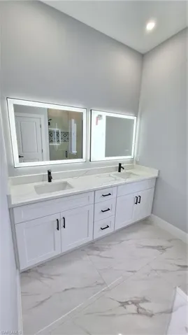 Full bath featuring double vanity, a sink, and a stall shower