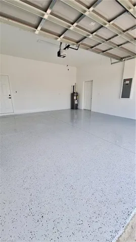 Garage featuring water heater, a garage door opener, and electric panel