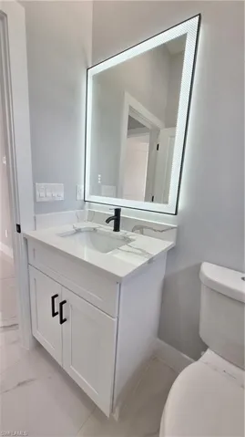 Bathroom with marble finish floor, toilet, and vanity