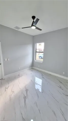 Unfurnished room with marble finish floor, a ceiling fan, baseboards, and visible vents