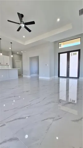 Unfurnished living room with recessed lighting, baseboards, a raised ceiling, ceiling fan, and visible vents