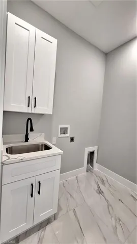 Clothes washing area with hookup for an electric dryer, baseboards, a sink, cabinet space, and washer hookup