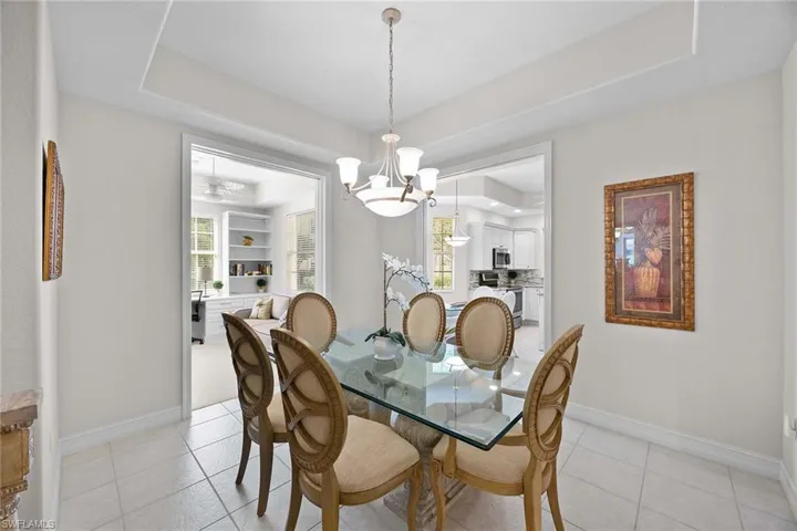 Dining area featuring a tray ceiling, light tile patterned flooring, a chandelier, and plenty of natural light