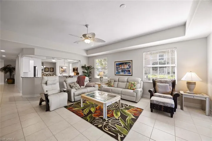 Living room featuring a ceiling fan, light tile patterned floors, and a tray ceiling