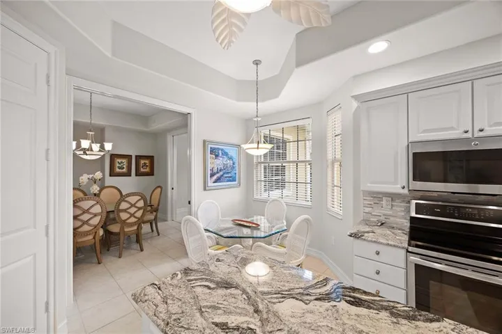 Dining room with a chandelier, light tile patterned floors, a raised ceiling, and recessed lighting