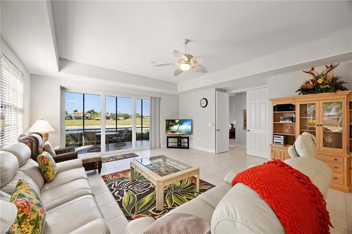 Living room with a tray ceiling, light tile patterned floors, and a ceiling fan
