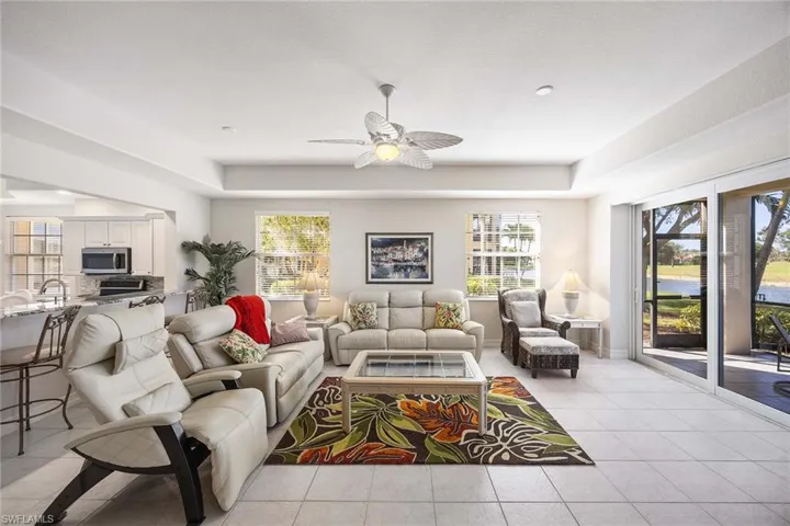 Living room with light tile patterned flooring, ceiling fan, and a water view