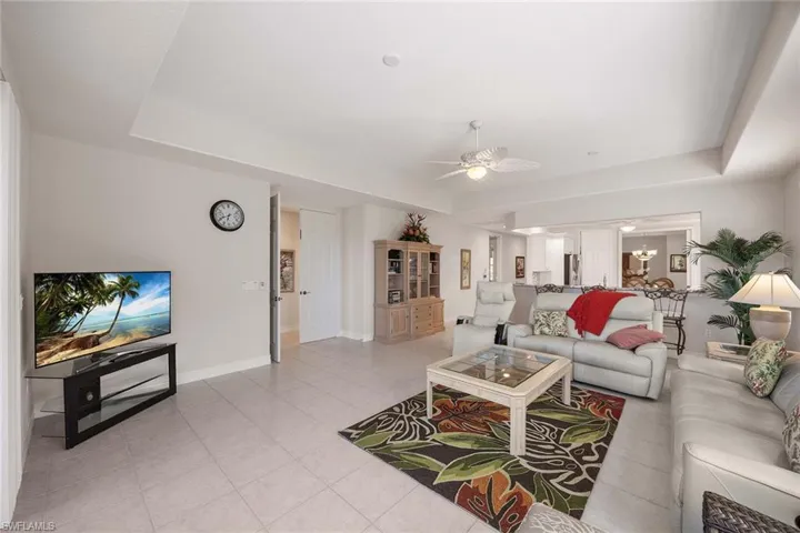 Living area featuring a tray ceiling, a ceiling fan, and light tile patterned flooring