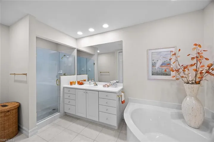 Bathroom featuring vanity, a shower stall, a garden tub, light tile patterned floors, and recessed lighting
