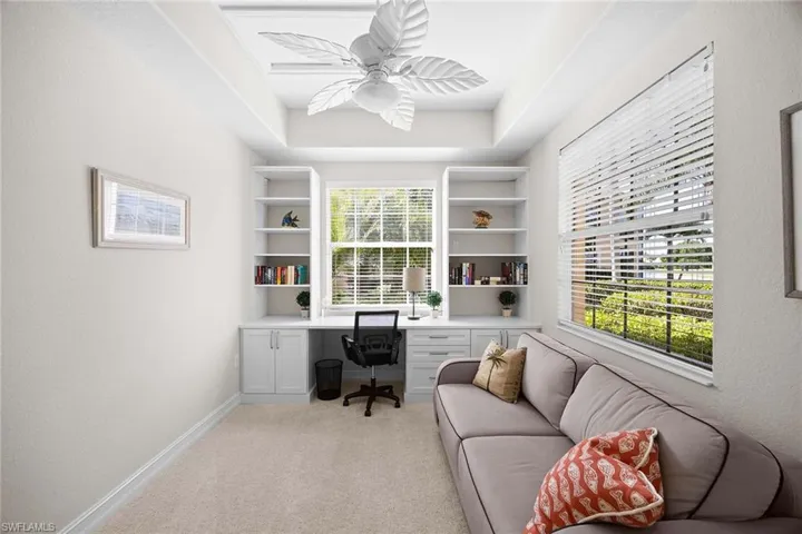 Office area featuring built in study area, ceiling fan, light carpet, and a textured wall