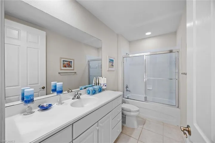 Bathroom with vanity, light tile patterned floors, and bath / shower combo with glass door