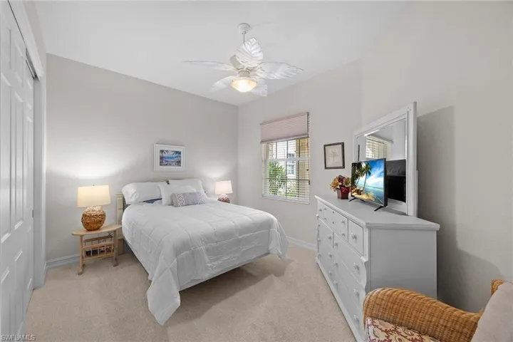 Bedroom with a closet, light colored carpet, and ceiling fan