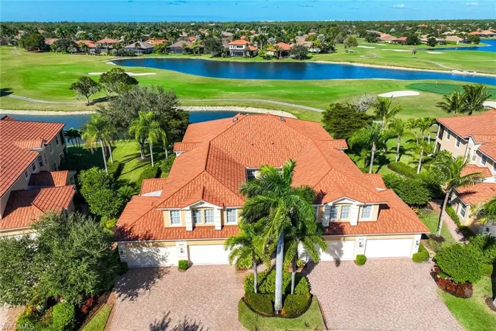Aerial view of residential area featuring a golf course and a nearby body of water