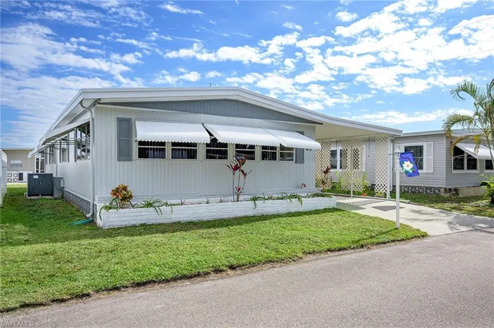 Manufactured / mobile home with central AC, a carport, and a front lawn