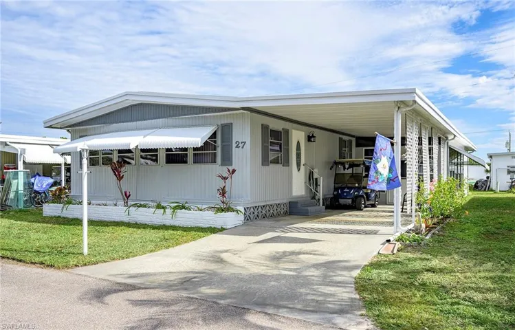 Manufactured / mobile home featuring a front lawn and a carport