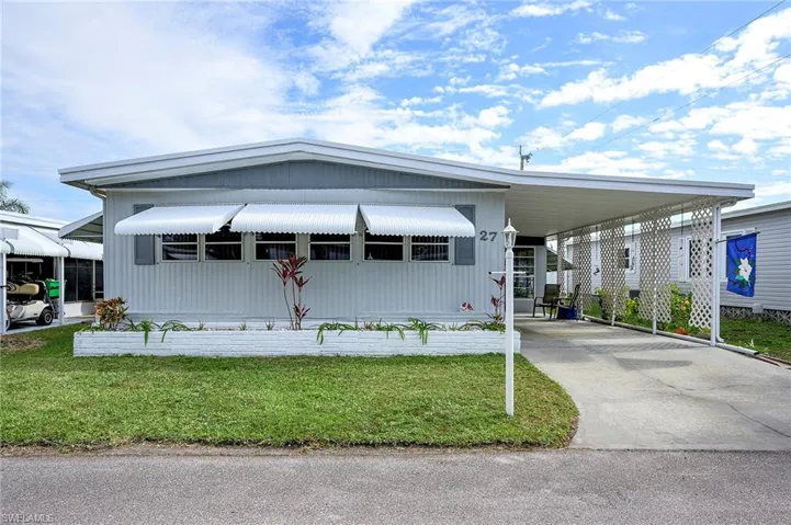 Manufactured / mobile home featuring a front lawn and a carport