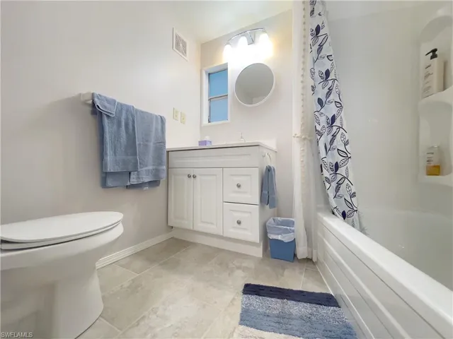 Full bathroom with toilet, shower / tub combo, tile patterned floors, and vanity