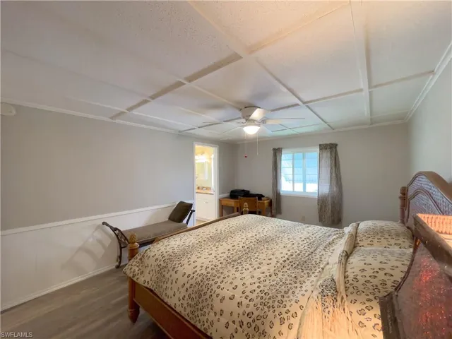 Bedroom with ceiling fan, wood-type flooring, and connected bathroom