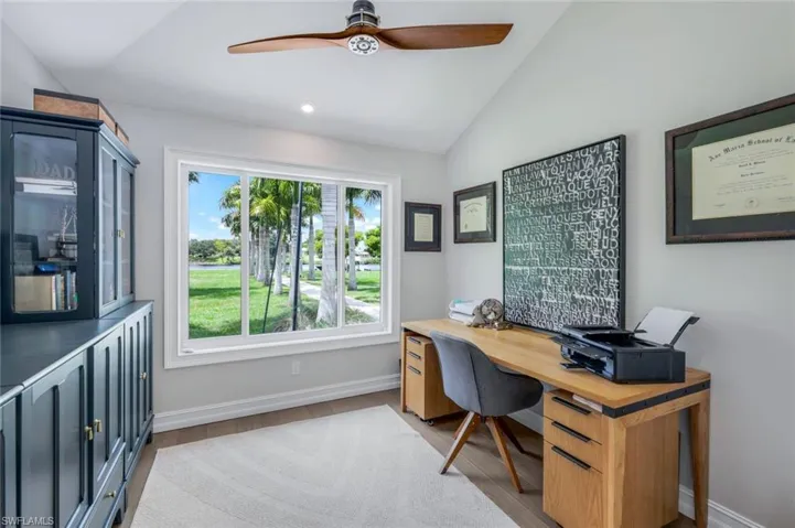 Home office with lofted ceiling, ceiling fan, and light wood-type flooring
