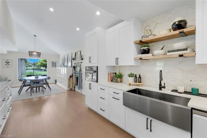 Kitchen featuring white cabinetry, backsplash, stainless steel oven, lofted ceiling, and light hardwood / wood-style floors