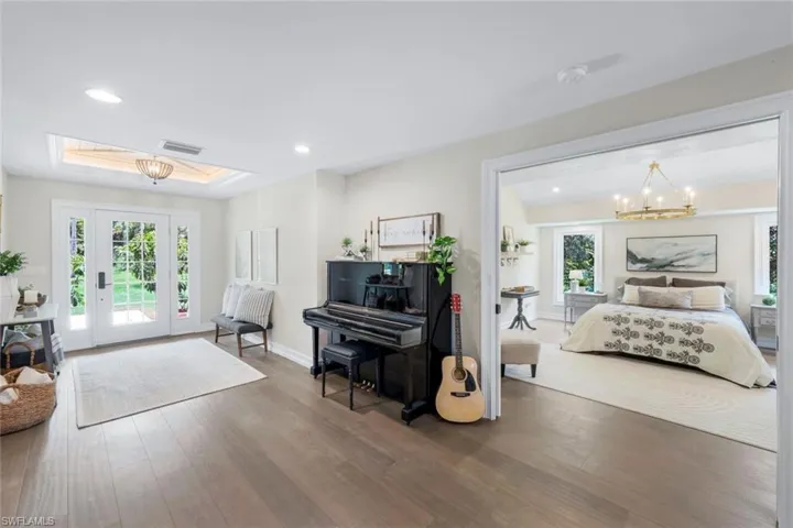 Bedroom with dark wood-type flooring, an inviting chandelier, access to outside, and a skylight