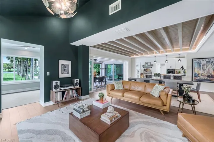 Living room with a wealth of natural light, hardwood / wood-style floors, beam ceiling, and a notable chandelier
