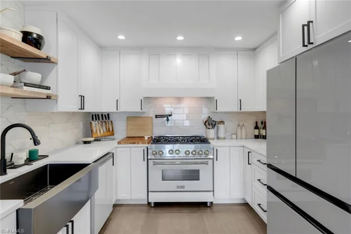Kitchen featuring white cabinets, light wood-type flooring, decorative backsplash, and high quality appliances