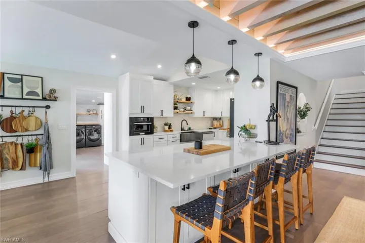 Kitchen featuring oven, white cabinetry, independent washer and dryer, kitchen peninsula, and a kitchen breakfast bar