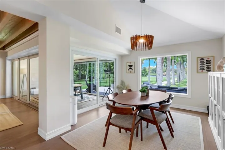 Dining area featuring high vaulted ceiling, hardwood / wood-style flooring, a chandelier, and beam ceiling