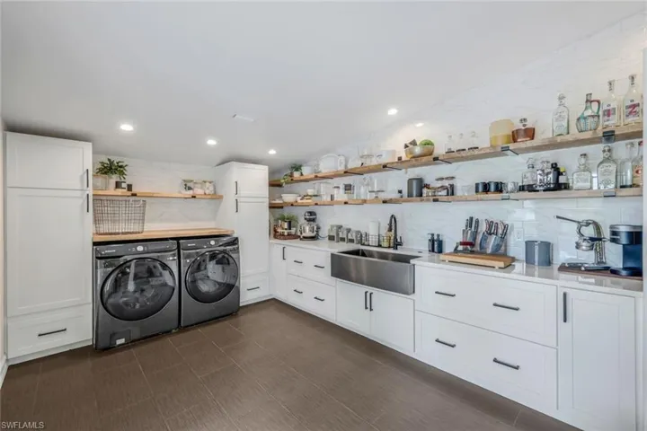 Laundry room with dark tile patterned floors, washing machine and dryer, and sink