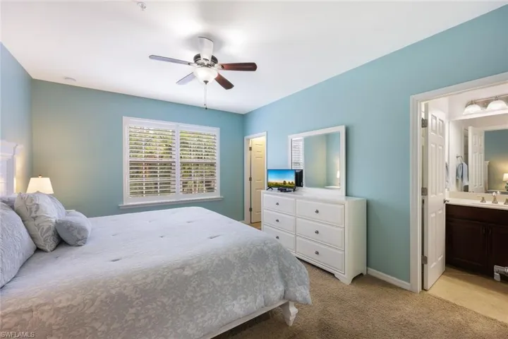 Bedroom with light carpet, connected bathroom, ceiling fan, and sink