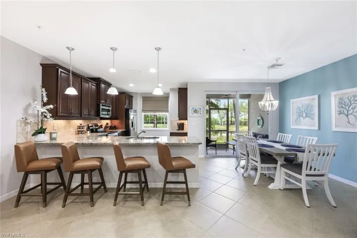 Kitchen featuring decorative backsplash, light tile patterned floors, light stone counters, and stainless steel appliances