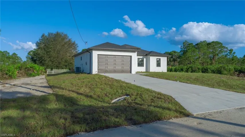 View of front of house with cooling unit, a front yard, and a garage