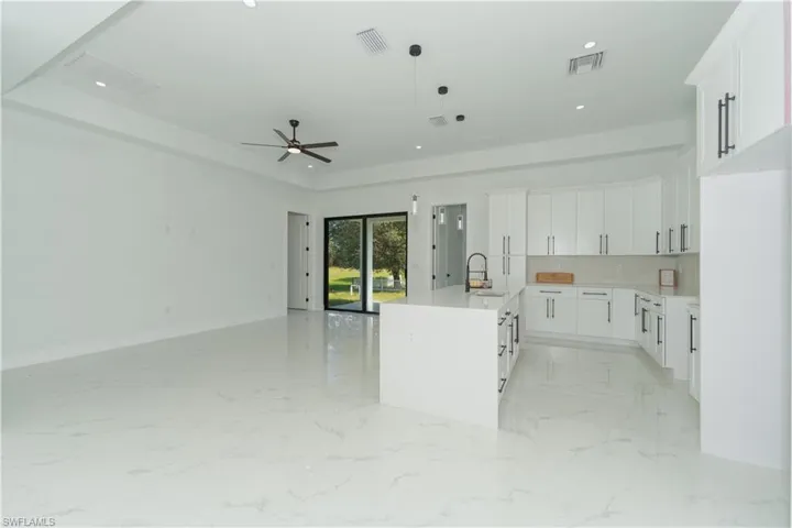 Kitchen featuring white cabinets, sink, a kitchen island with sink, ceiling fan, and decorative light fixtures