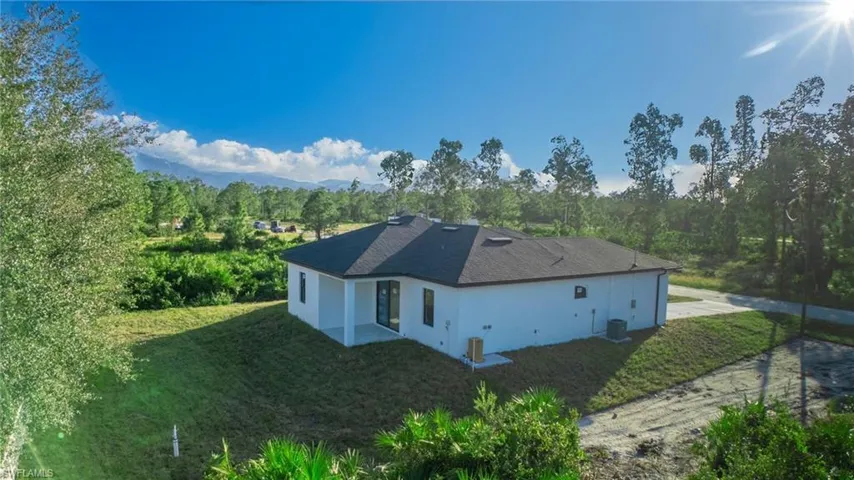 View of side of property featuring a yard and cooling unit