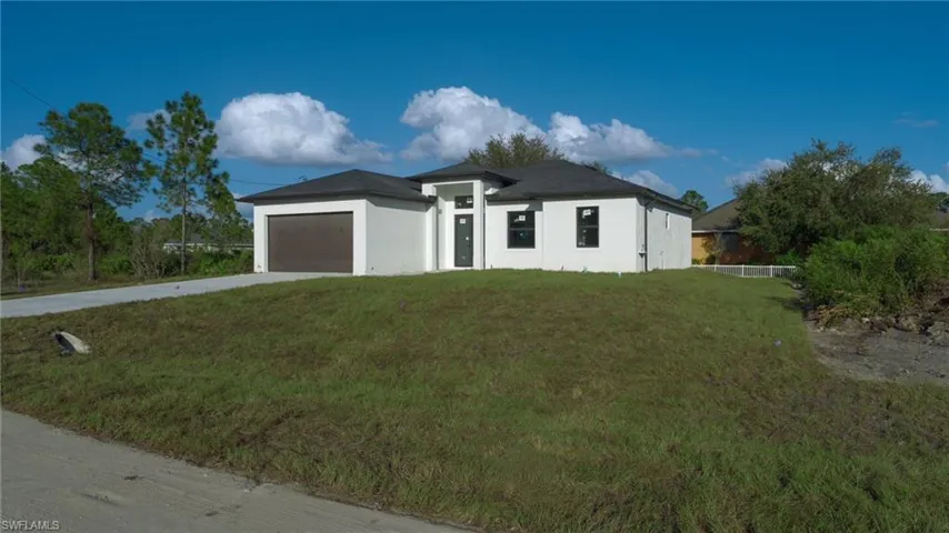 View of front of home with a garage and a front lawn