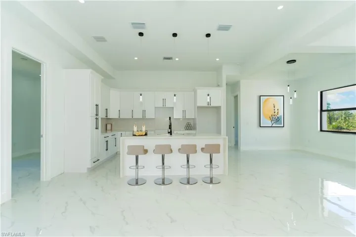 Kitchen with white cabinetry, pendant lighting, and a kitchen island with sink