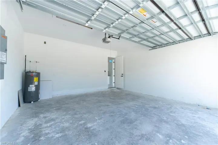 Garage featuring electric water heater and a garage door opener