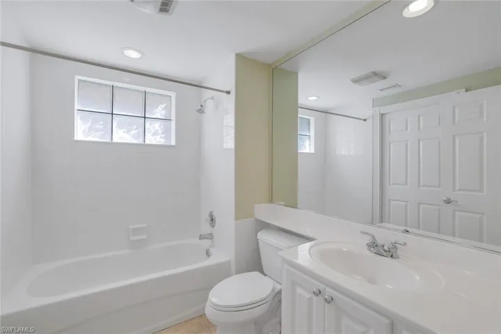 Full bathroom featuring tile patterned flooring, tiled shower / bath combo, vanity, and toilet