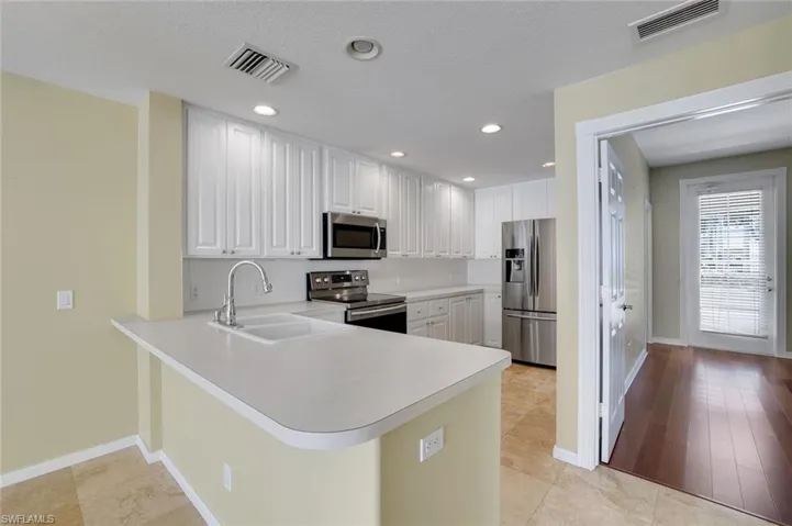 Kitchen featuring sink, kitchen peninsula, light hardwood / wood-style flooring, white cabinetry, and stainless steel appliances