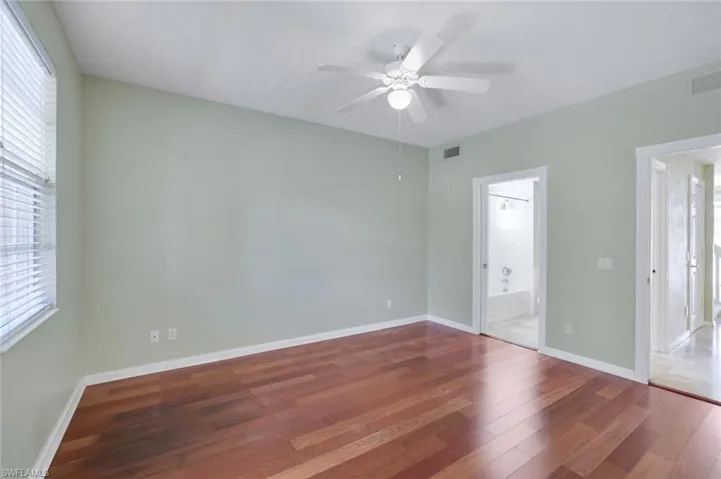 Unfurnished bedroom with wood-type flooring, ceiling fan, and ensuite bathroom