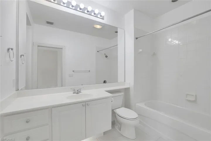 Full bathroom featuring vanity, tiled shower / bath combo, toilet, and tile patterned floors