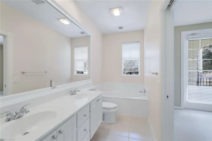 Bathroom with vanity, tile patterned flooring, a washtub, and toilet